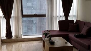 Uma sala de estar com sofá, mesa de centro e janela com cortinas.
