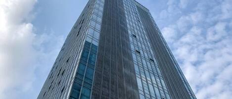 A tall, modern skyscraper with a glass facade and a clear sky in the background.