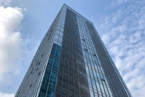 Un grattacielo moderno e slanciato, con facciata in vetro e cielo sereno sullo sfondo.