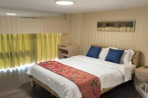 Een hotelkamer met een bed, een bureau en een raam met gordijnen.