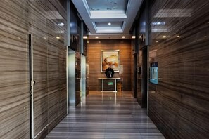 A hallway with a wooden wall, a clock, and a television screen.