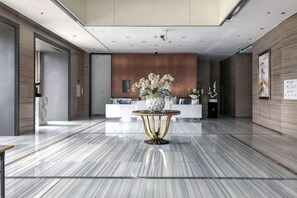 A hotel lobby with a reception desk, a marble floor, and a decorative table with flowers. - Fusion International Garden Apartment（Qingpu Branch Of Zhongshan Hospital） (Shanghai)