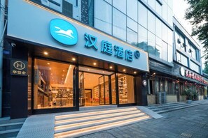 A hotel entrance with a large sign, glass doors, and a staircase leading up to the entrance. - HanTing Hotel (Dujiangyan) (Dujiangyan)