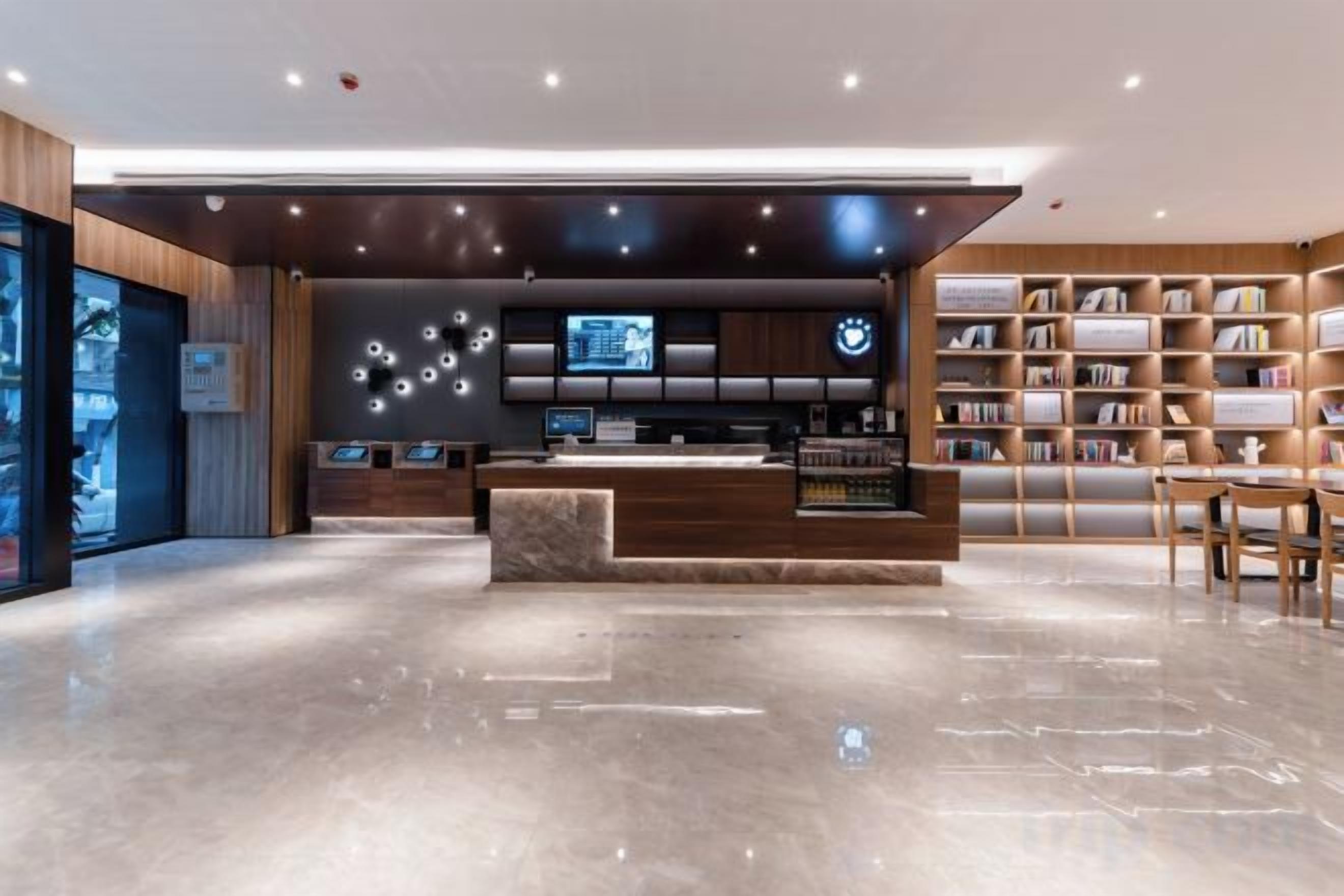 Un área de recepción moderna con piso de mármol, mostrador de madera y una estantería llena de libros.