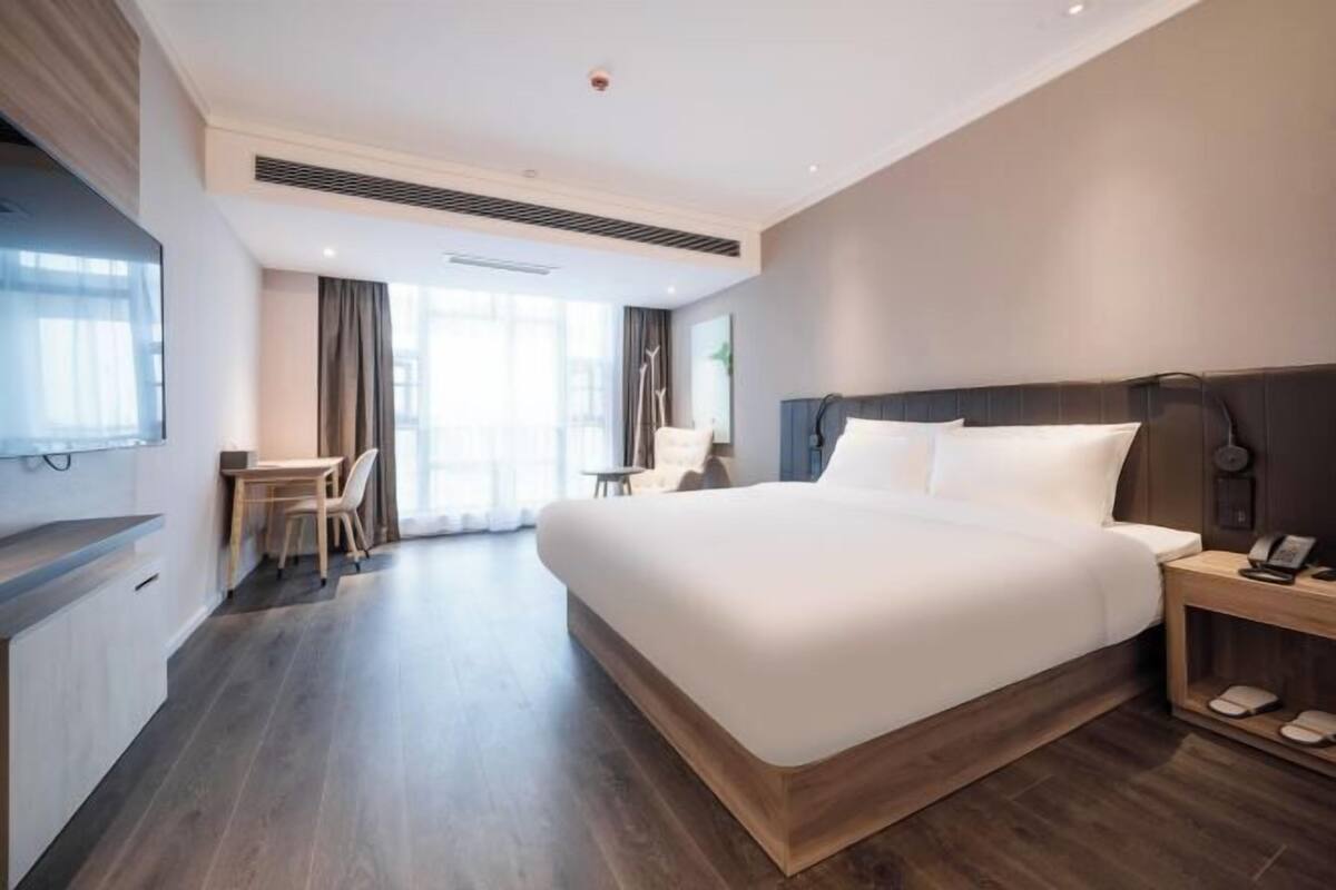 Ein modernes Hotelzimmer mit einem großen Bett, einem Schreibtisch und einem Sessel.
