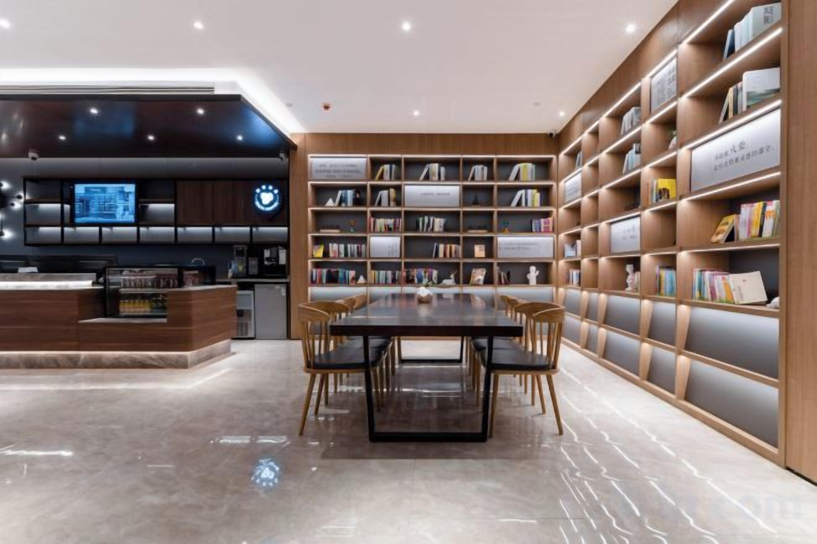 Una biblioteca moderna con una mesa central y sillas, rodeada de estanterías.