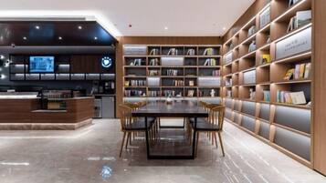 Una biblioteca moderna con una mesa central y sillas, rodeada de estanterías.