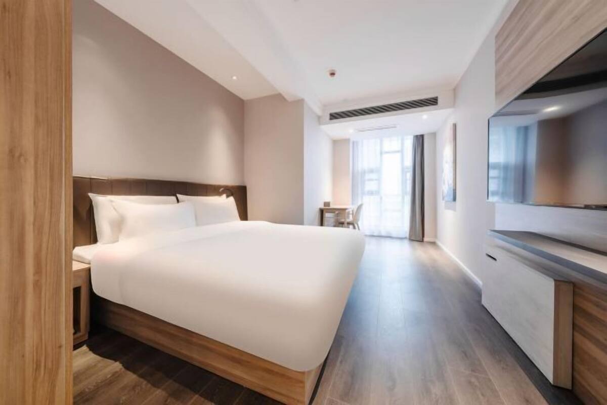 Ein modernes Hotelzimmer mit einem großen Bett, einem Schreibtisch und einem Fernseher.
