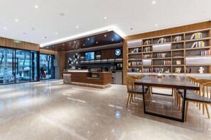 A modern library with a reception desk, bookshelves, and a dining area. - HanTing Hotel (Dujiangyan) (Dujiangyan)