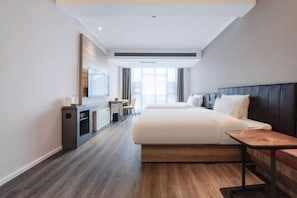 Ein modernes Hotelzimmer mit einem großen Bett, einem Schreibtisch und einem Fernseher.