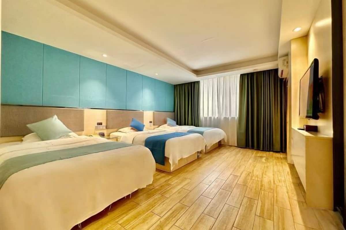 Una habitación de hotel con tres camas, un televisor de pantalla plana y un ventanal grande con cortinas.