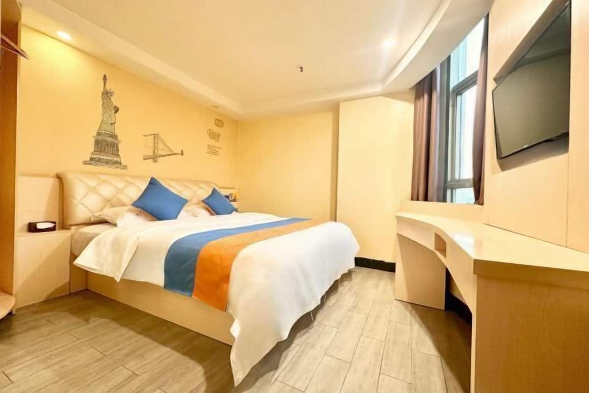 Habitación de hotel con cama, escritorio, televisor y un mural con una estatua y una ilustración de un puente.