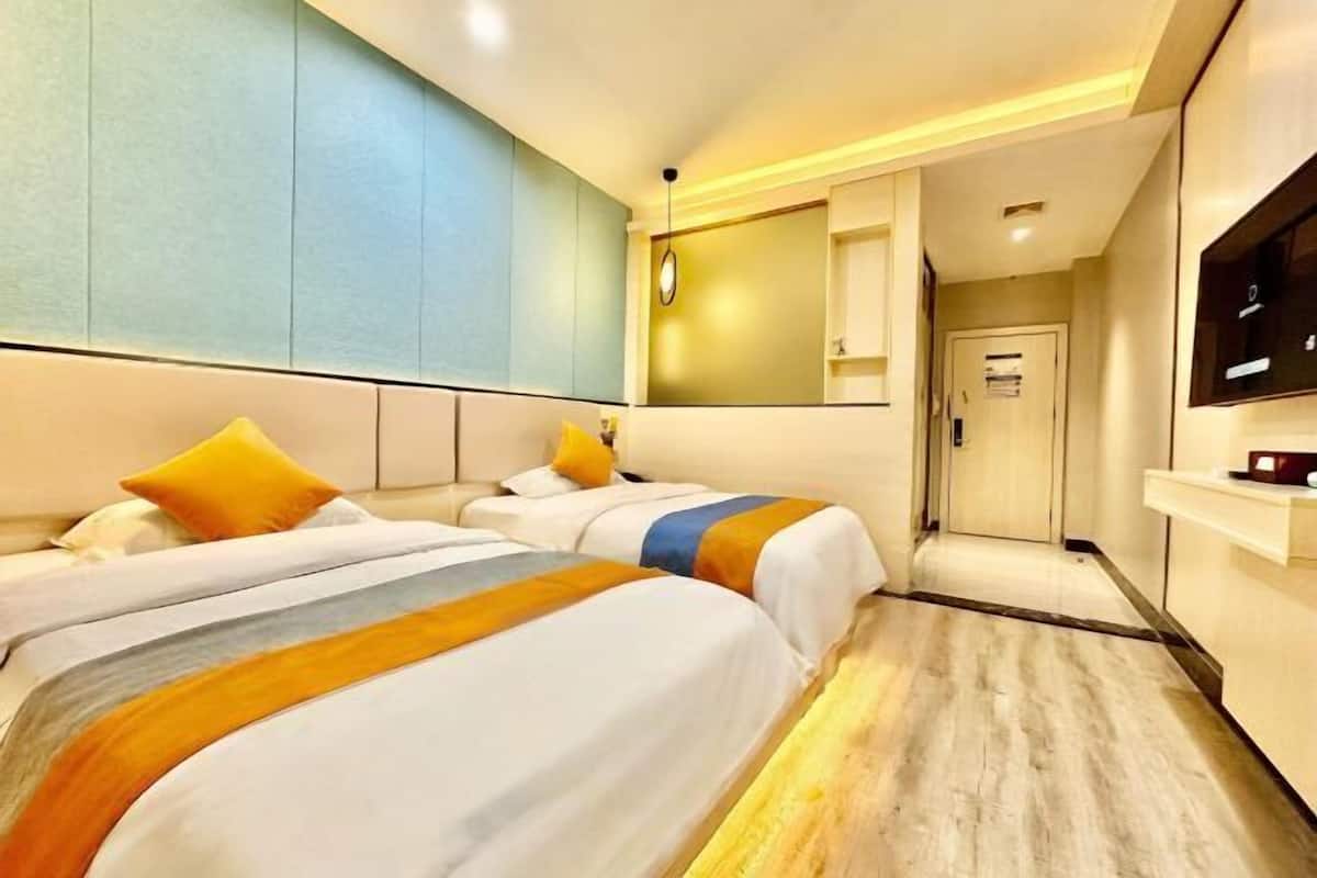 Habitación de hotel con dos camas, un televisor, un espejo y una puerta que da a un pasillo.