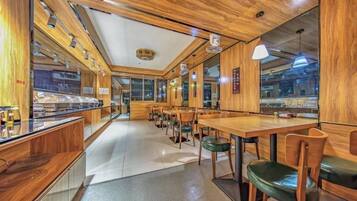 Interior de restaurante con paneles de madera, mostrador de buffet y mesas dispuestas.
