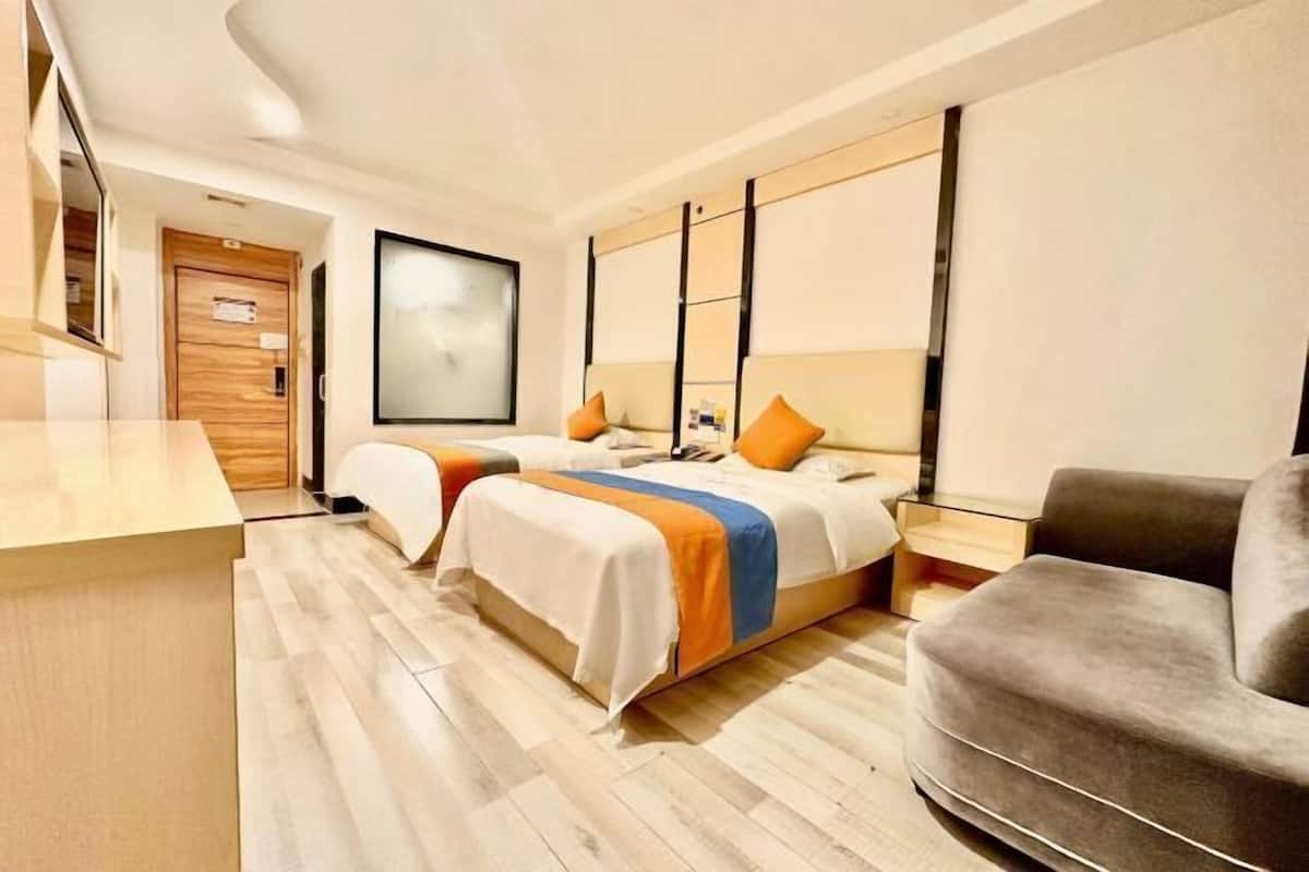 Una habitación de hotel moderna con una cama grande, un sofá, un escritorio y un ventanal amplio.