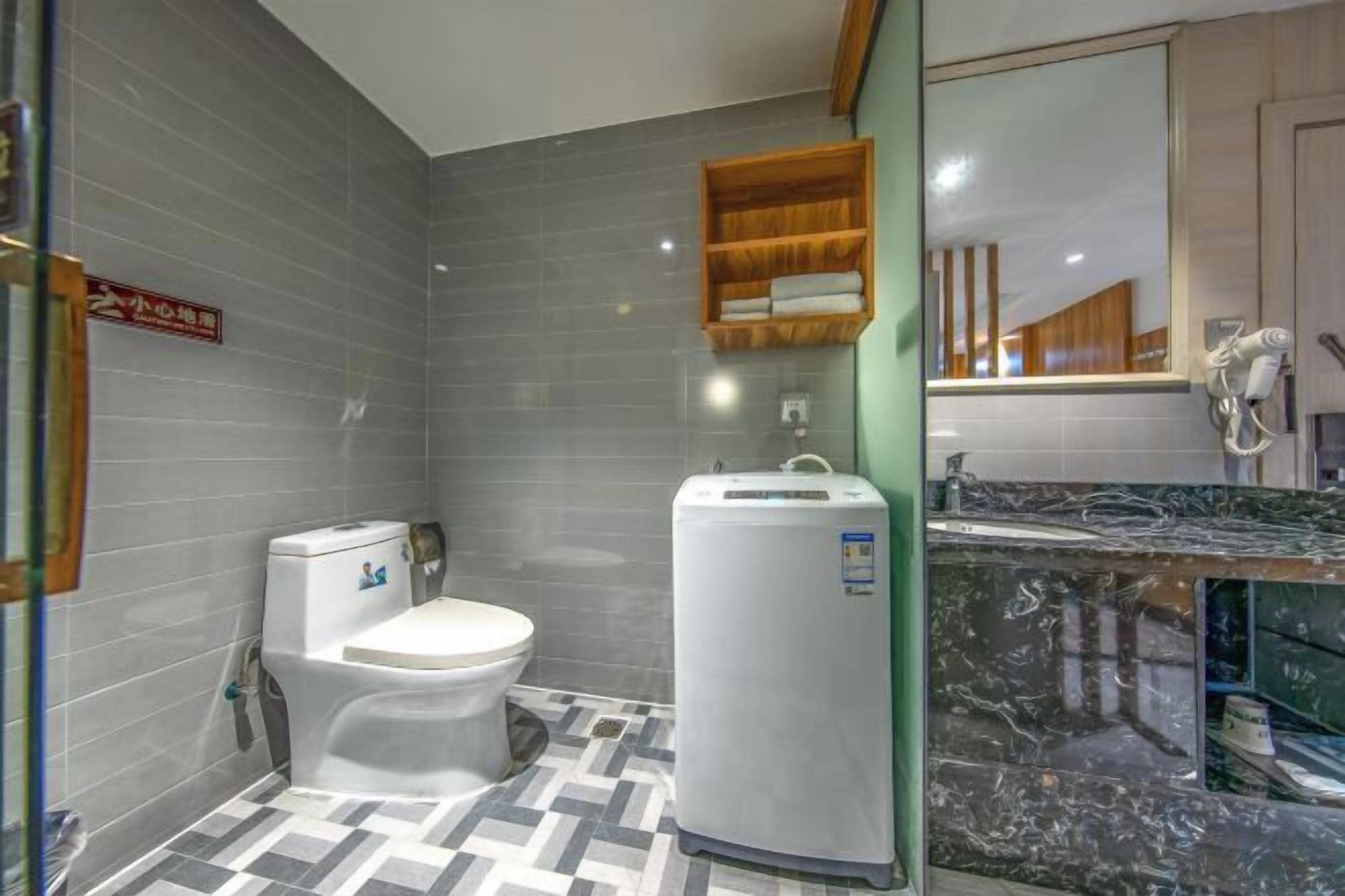 A bathroom with a toilet, a white pedestal water heater, and a marble countertop.