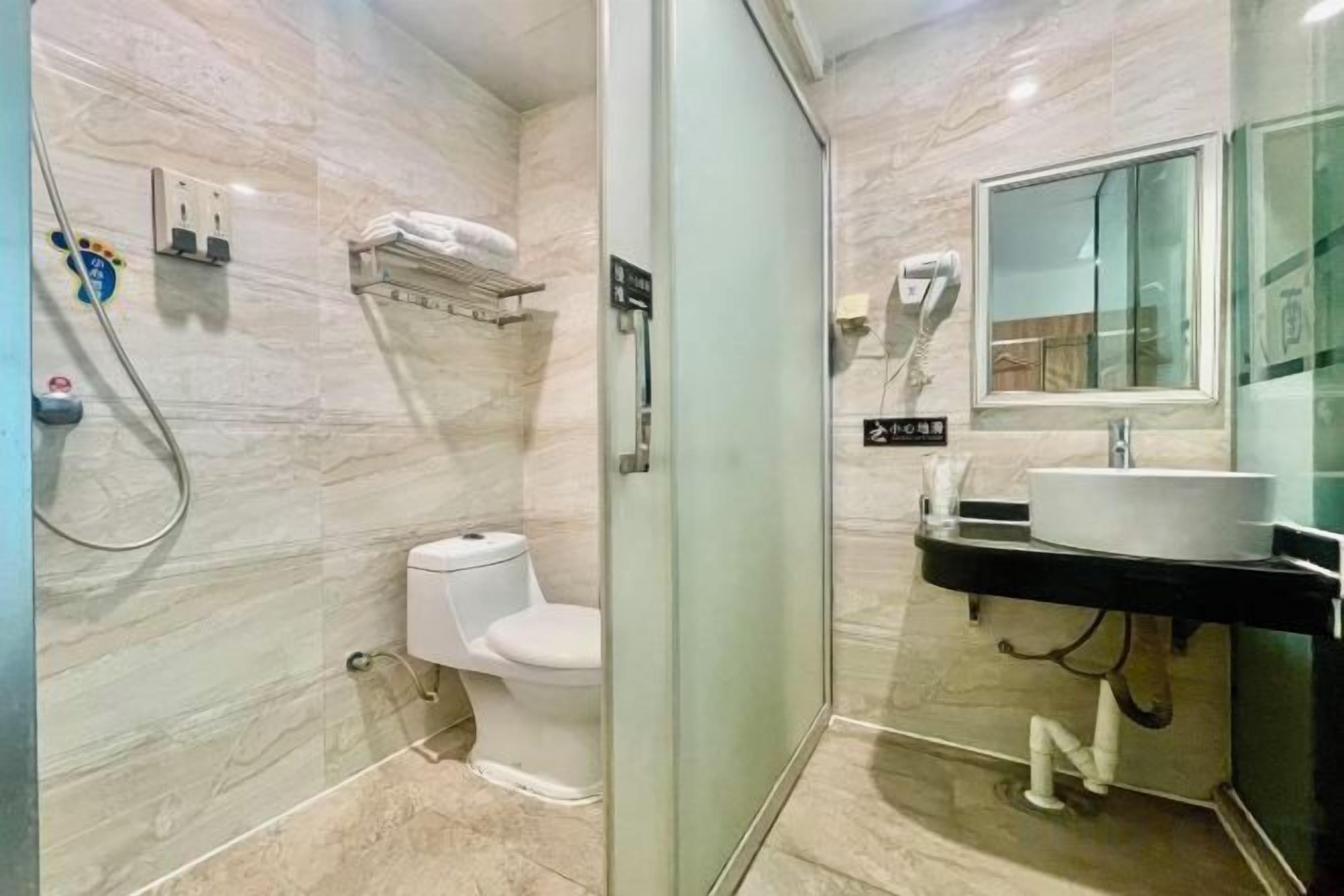 Un baño moderno con cabina de ducha de vidrio, inodoro, lavabo con espejo y perchero para toallas.
