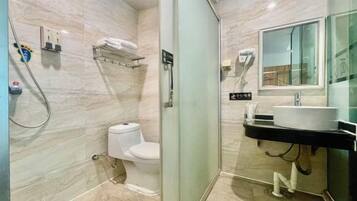 Un baño moderno con cabina de ducha de vidrio, inodoro, lavabo con espejo y perchero para toallas.