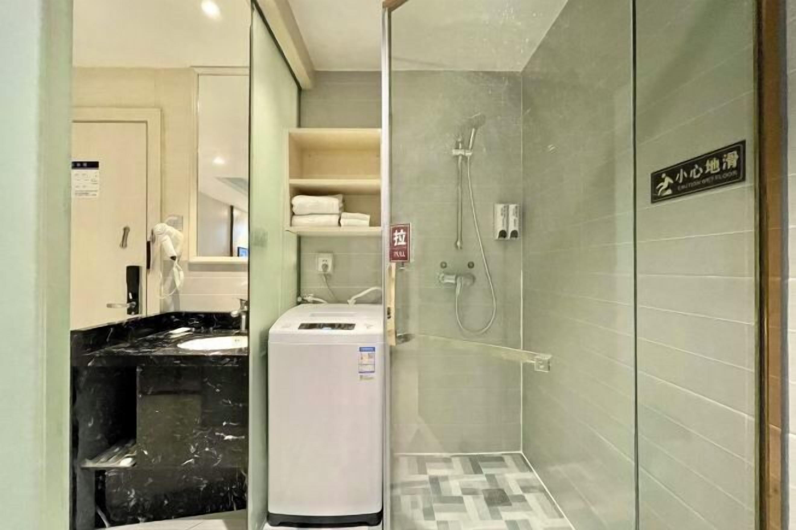Un baño moderno con ducha de vidrio, dispensador de toallas blanco y lavabo de mármol.