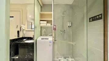 Un baño moderno con ducha de vidrio, dispensador de toallas blanco y lavabo de mármol.