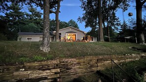 A house with a covered porch, a wooden fence, and a stack of firewood.