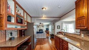 A spacious kitchen with wooden cabinets, granite countertops, and a central island.