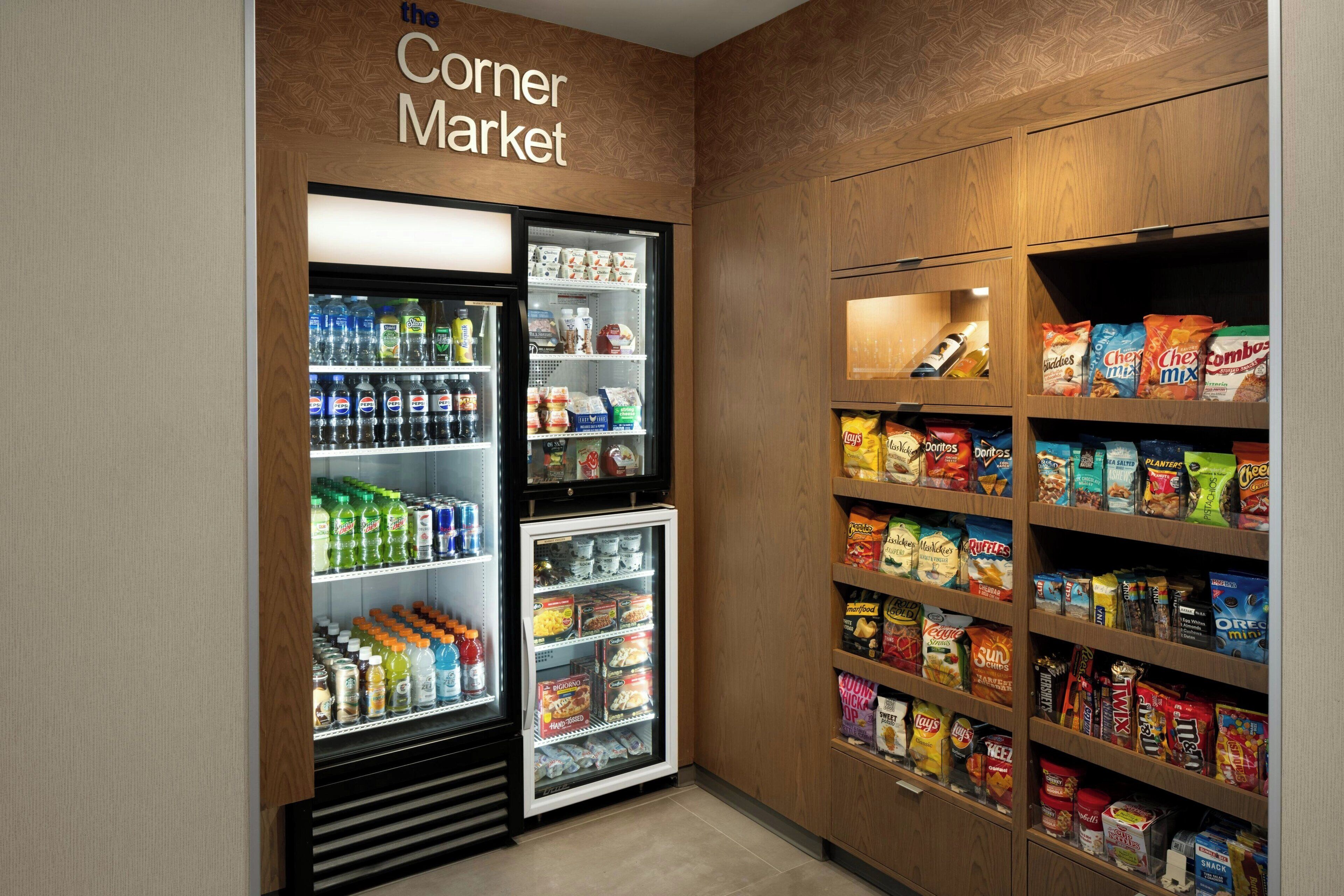 A corner market with refrigerated beverage dispensers and shelves stocked with snacks and chips.