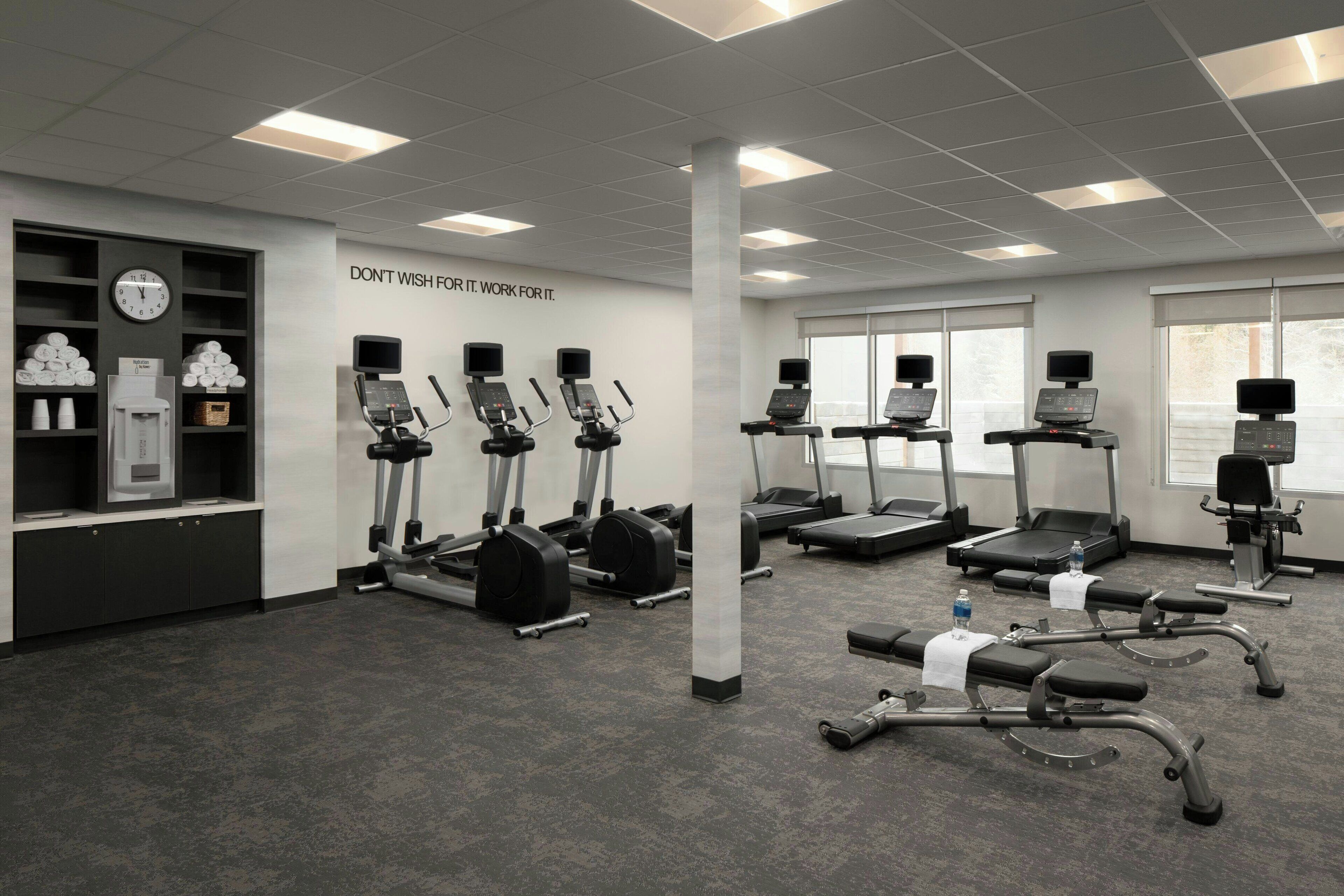 A modern gym with treadmills, elliptical machines, and weight benches.