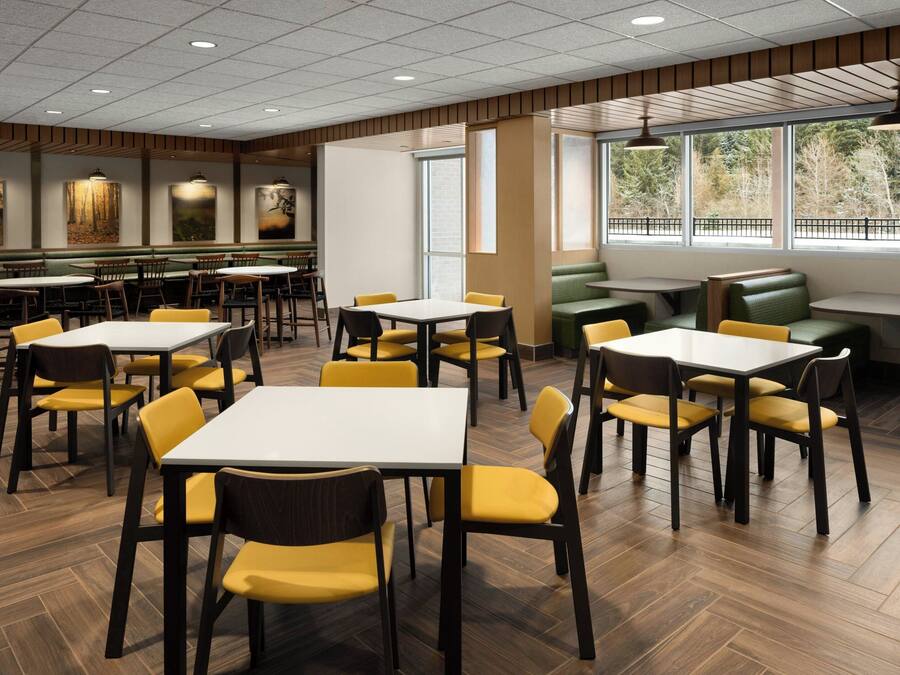 A restaurant with booths and tables, wooden flooring, and artwork on the walls.