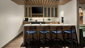 A modern kitchen with wooden cabinets, a central island with bar stools, and a large flat-screen TV. - Fairfield by Marriott Inn & Suites Traverse City (Traverse City)