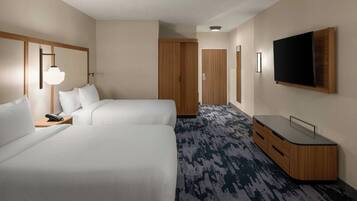 A hotel room with two beds, a desk, a TV, and a wardrobe.