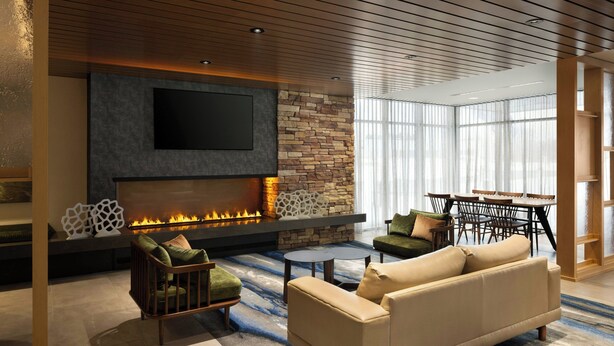 A modern living room with a fireplace, comfortable seating, and a large window providing natural light. - Fairfield by Marriott Inn & Suites Traverse City (Traverse City)