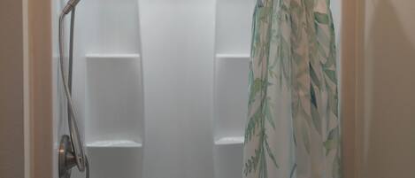 A shower with a handheld showerhead and a bamboo-patterned shower curtain.