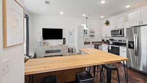A modern kitchen with a wooden island, stainless steel appliances, and bar stools.