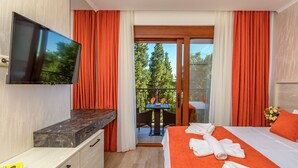 Ein Hotelzimmer mit Bett, Fernseher, Schreibtisch und einem Balkon mit Tisch und Stühlen.