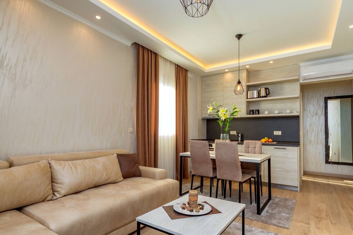 A modern living room with a sofa, a dining table with chairs, and a kitchen area with a dining table and chairs.