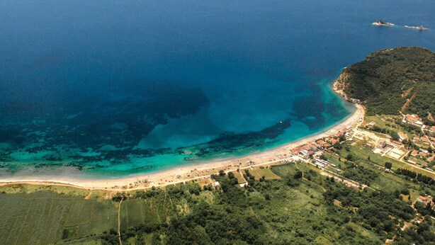 Luftaufnahme einer Küstenstadt mit Strand, klarem blauen Wasser und einer kleinen Insel.