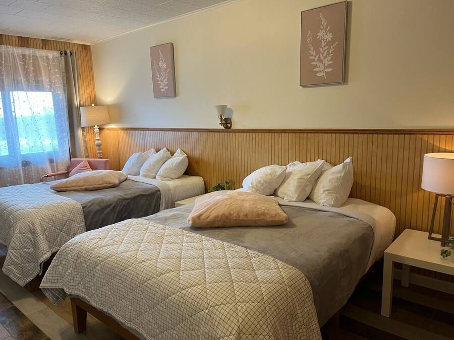 Hotelkamer met twee eenpersoonsbedden, een houten hoofdeinde, een nachtkastje met lamp en twee wandlampen.
