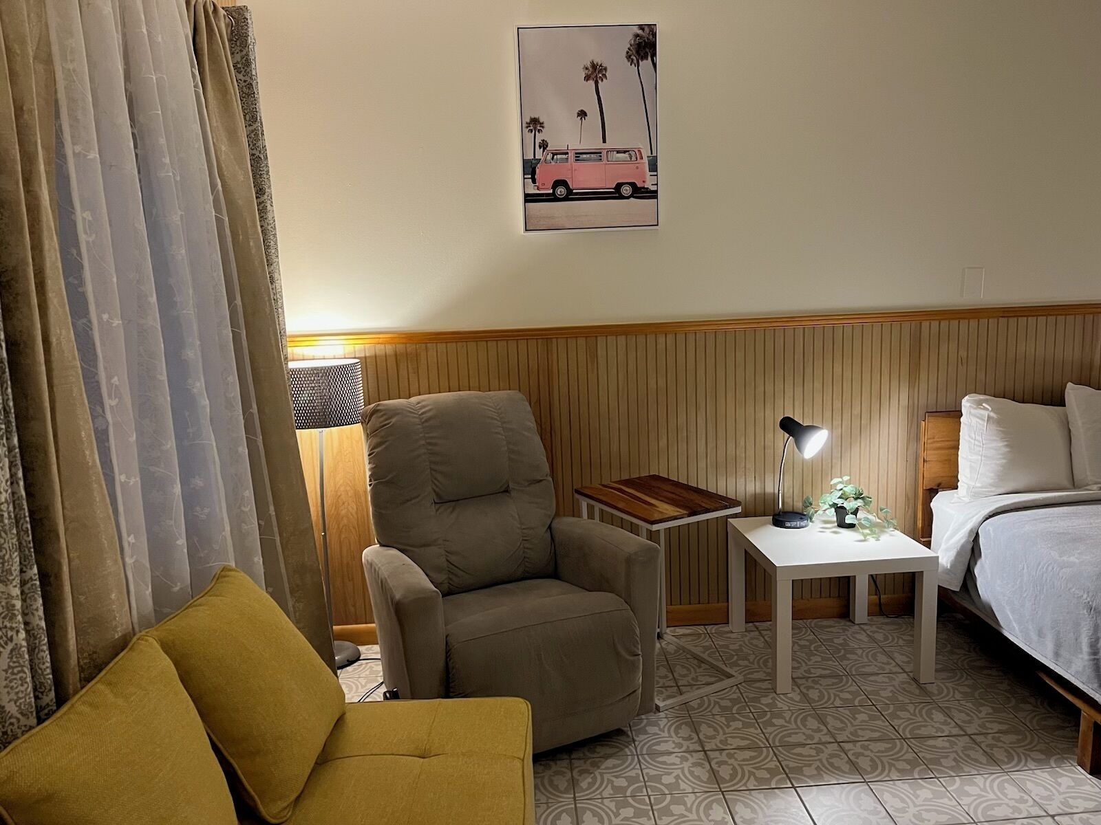 Una habitación de hotel con cama, escritorio, silla y sofá.