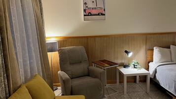 Una habitación de hotel con cama, escritorio, silla y sofá.