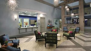 A spacious lobby with a reception desk, multiple seating areas, and a high ceiling with exposed beams.