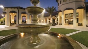 A fountain in a courtyard with a building in the background.