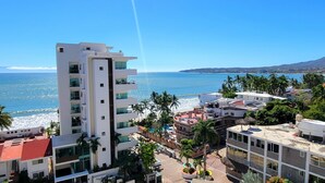 A high-rise hotel with balconies overlooking a beach and ocean.