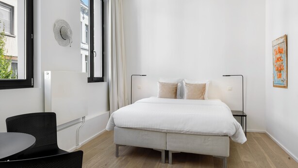 A modern bedroom with a bed, bedside tables, a chair, and a window. - The 1880 Boutique Holiday Home in The Heart of Antwerp (Antwerpen)