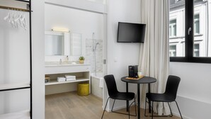 A modern bathroom with a shower, toilet, and sink. There is a TV mounted on the wall and a small table with two chairs. - The 1880 Boutique Holiday Home in The Heart of Antwerp (Antwerpen)