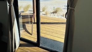 A room with a large sliding glass door leading to a wooden deck overlooking a beach. - Melbourne Beach Resort & Surf Club  (Melbourne Beach)