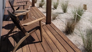 A wooden deck with a table and chairs overlooking a beach. - Melbourne Beach Resort & Surf Club  (Melbourne Beach)