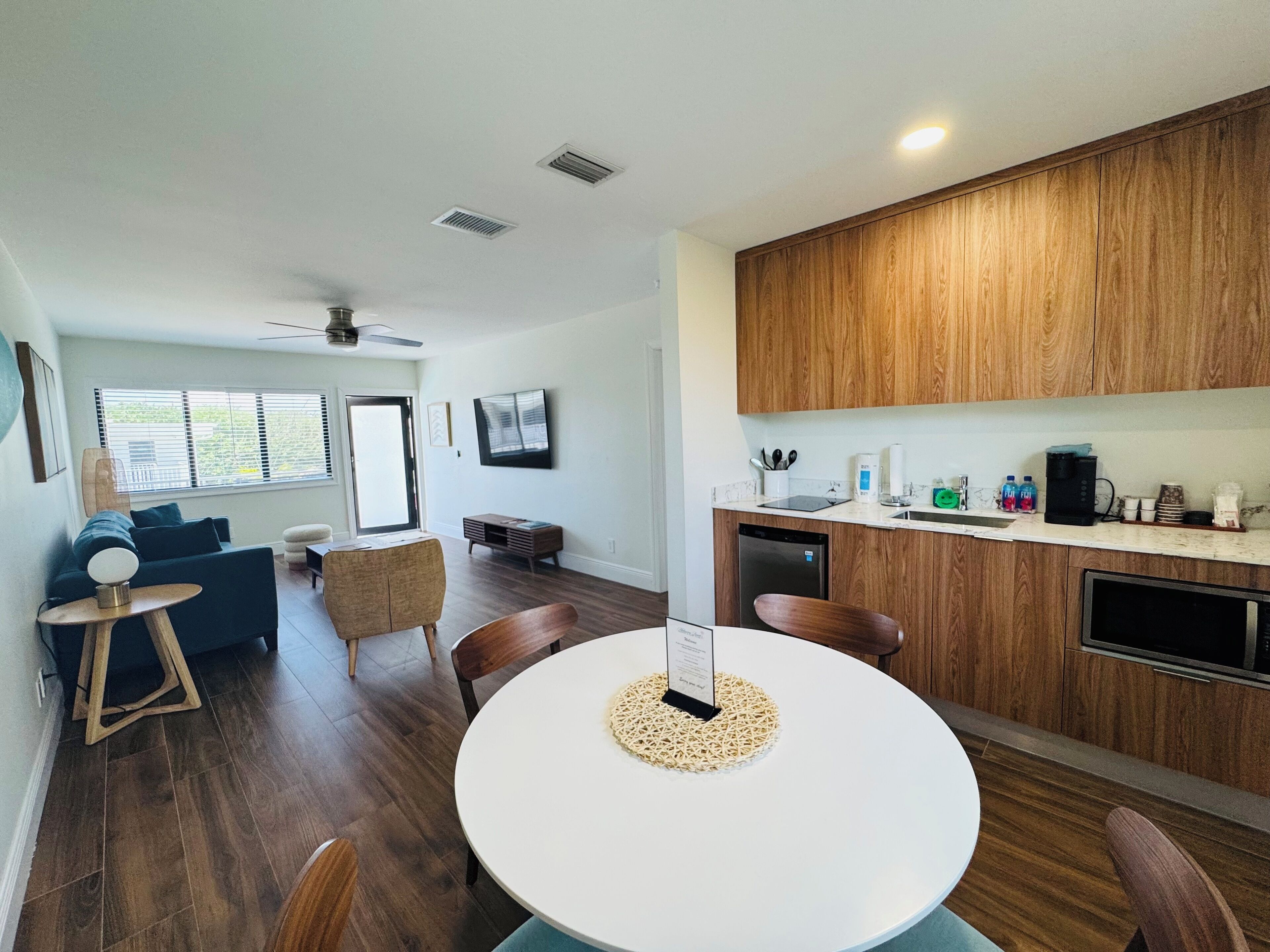 A modern kitchen with wooden cabinets, a dining table with chairs, and a built-in dishwasher.