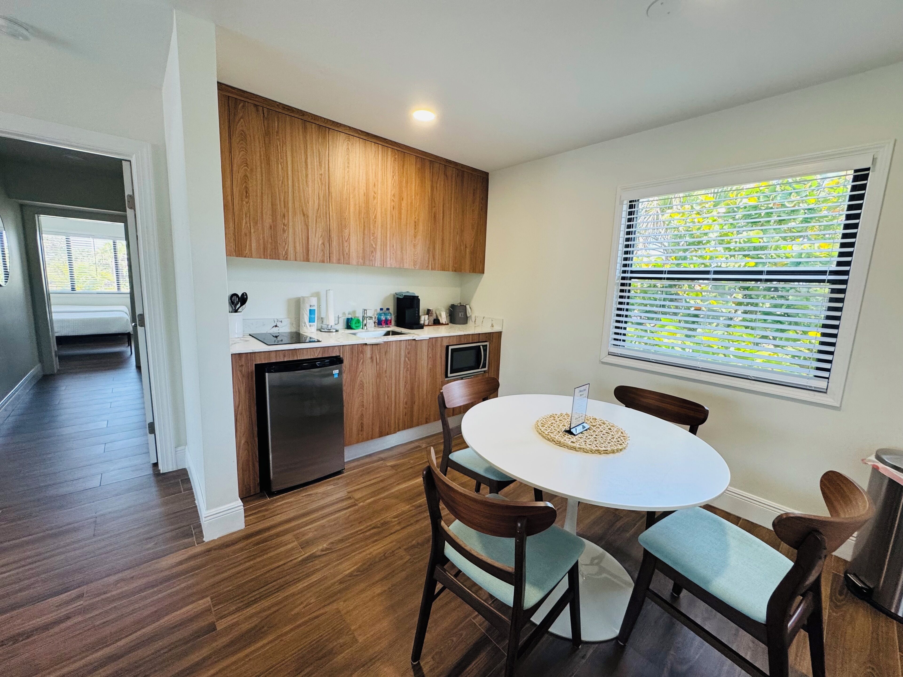A modern kitchen with wooden cabinets, a built-in dishwasher, and a dining area with a round table and four chairs.