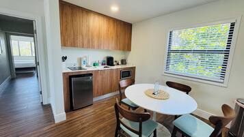 A modern kitchen with wooden cabinets, a built-in dishwasher, and a dining area with a round table and four chairs.